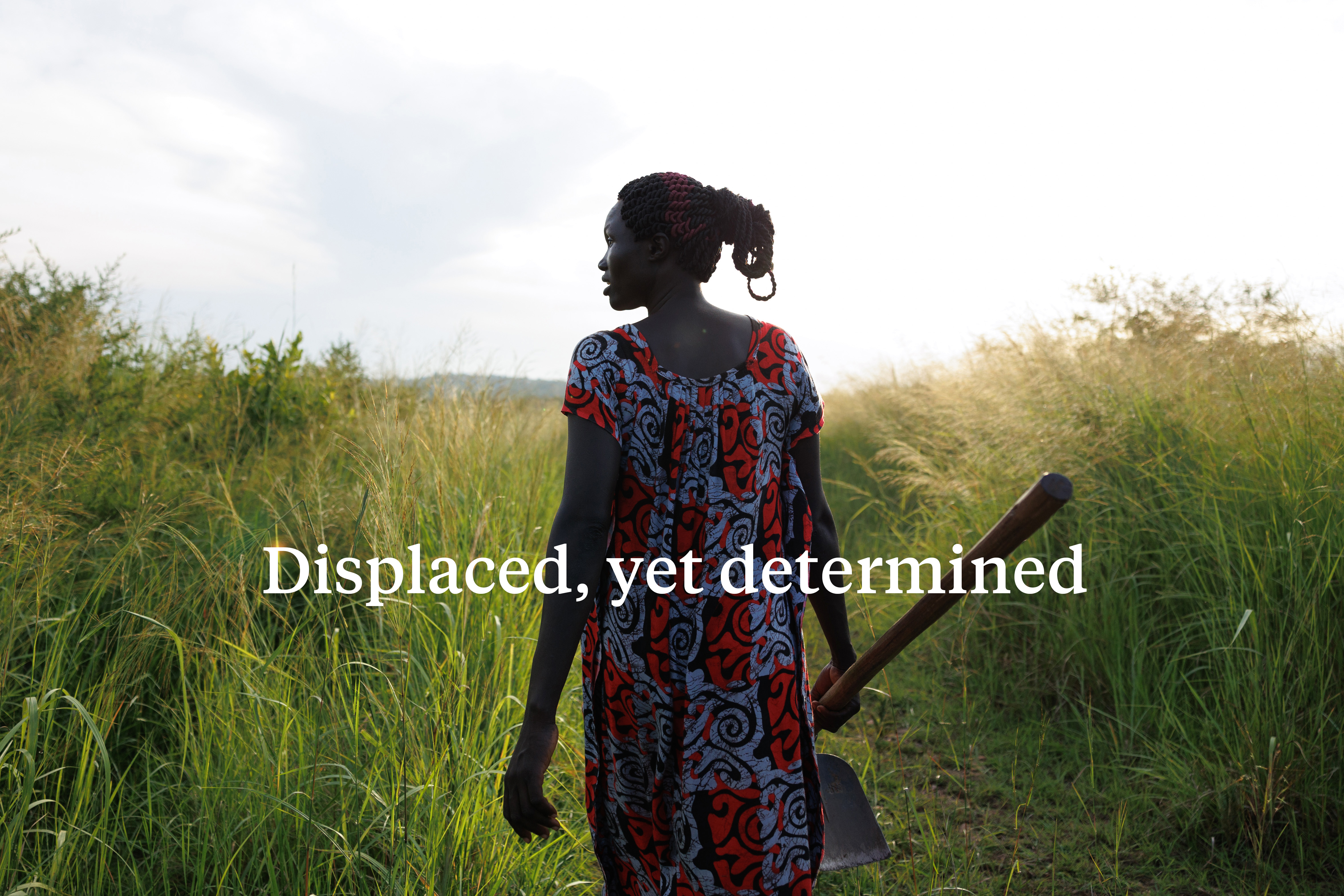 Silhouette of ugandan woman walking through field.