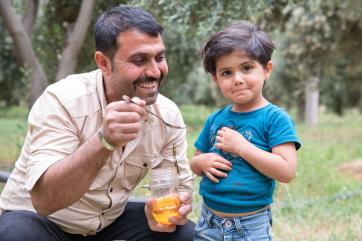 A beekeeper gives homemade honey to their child.  