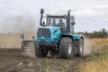 Farming tractor moves through field.