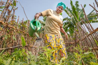 Woman watering crops with a watering can.
