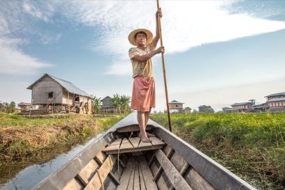 Man guides boat through waterway.