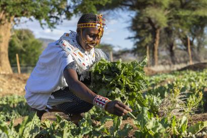 Kenyan woman working in agricultural setting, smiling.