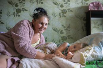A mother wakes her child from a nap.