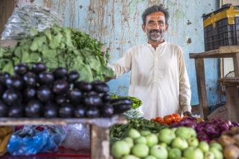 Pakistania man stands behind his merchandise in his vegetable stall.