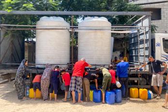 Palestinians filling jerrycans from water tender truck.