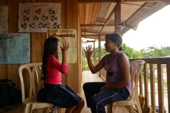 Lucia and her best friend elena, seated in chairs facing each other, playing a game