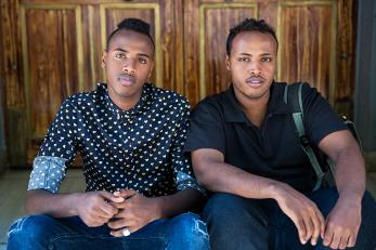 Abdi and yasin sitting next to each other with arms resting on their knees
