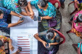 People sitting at tables using mobile devices.