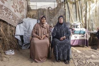 Two Palestinian women sit outside their tent in Gaza.