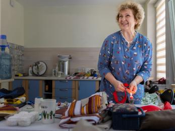 A person making traditional Ukrainian dolls and clothing in their home.
