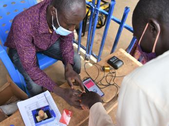 A mercy corps team member assists an e-voucher recipient with a digital identity process, increasing security and efficiency.