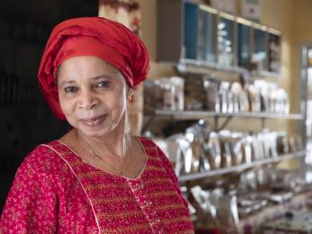 Senegalese female entrepreneur stands in her business smiling.