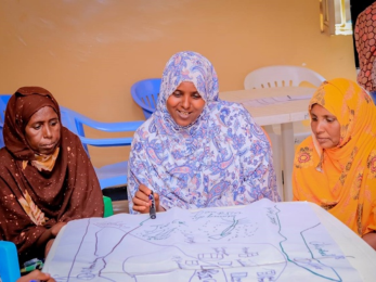 Three individuals discuss the regional livestock program at a table.