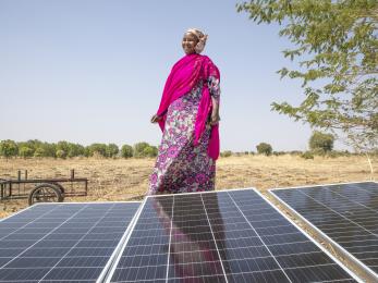 Nigerian woman standing behind a solar panel.